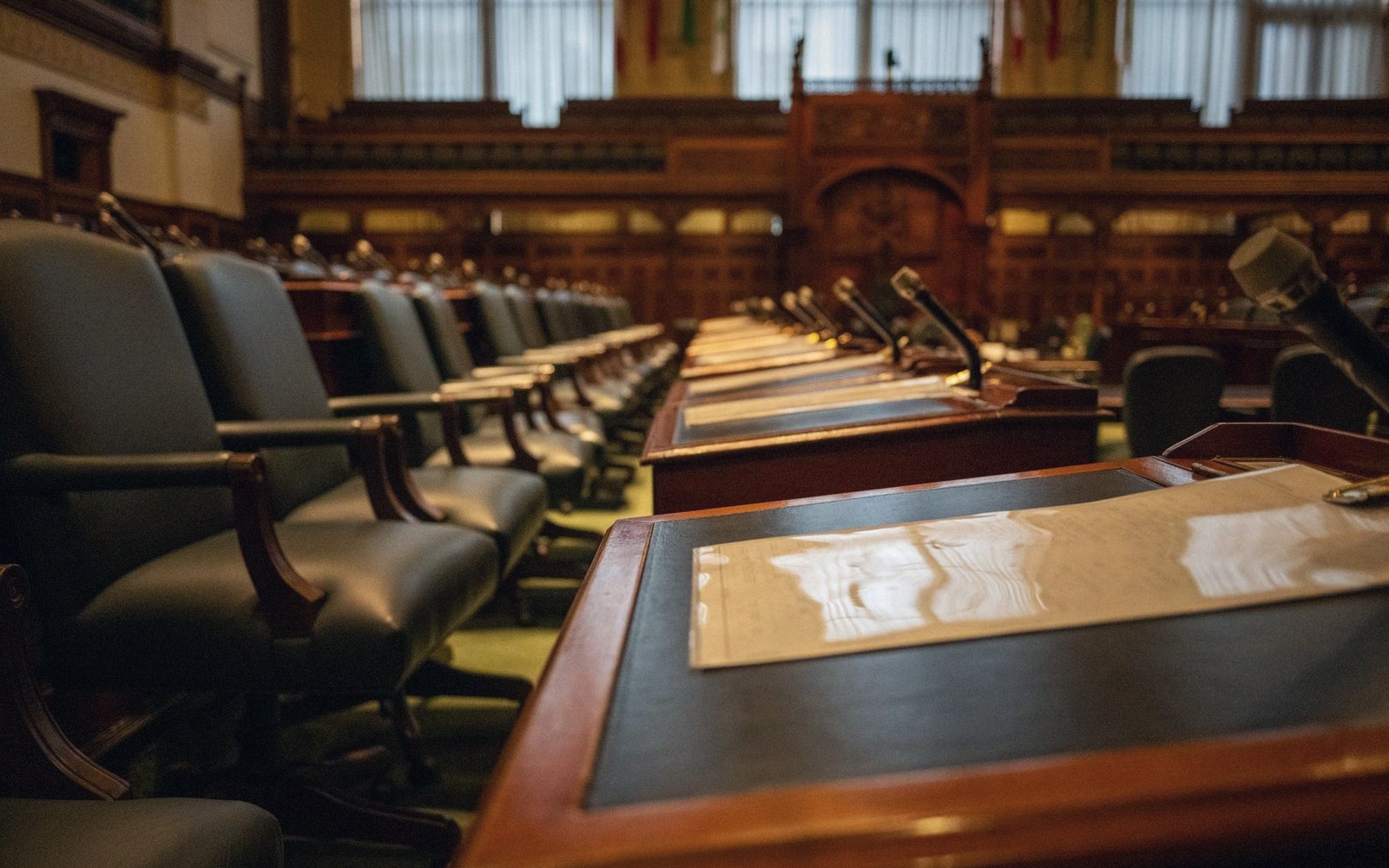 An empty committee room with microphones and blotters